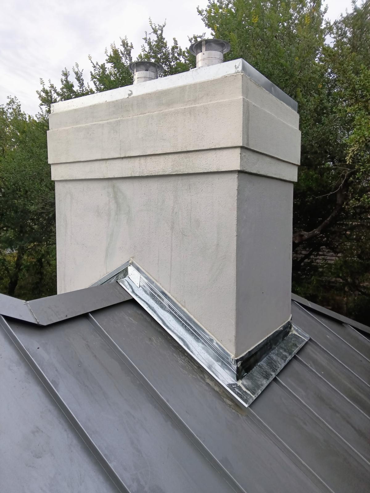 Stucco chimney with new metal flashing on a standing seam roof