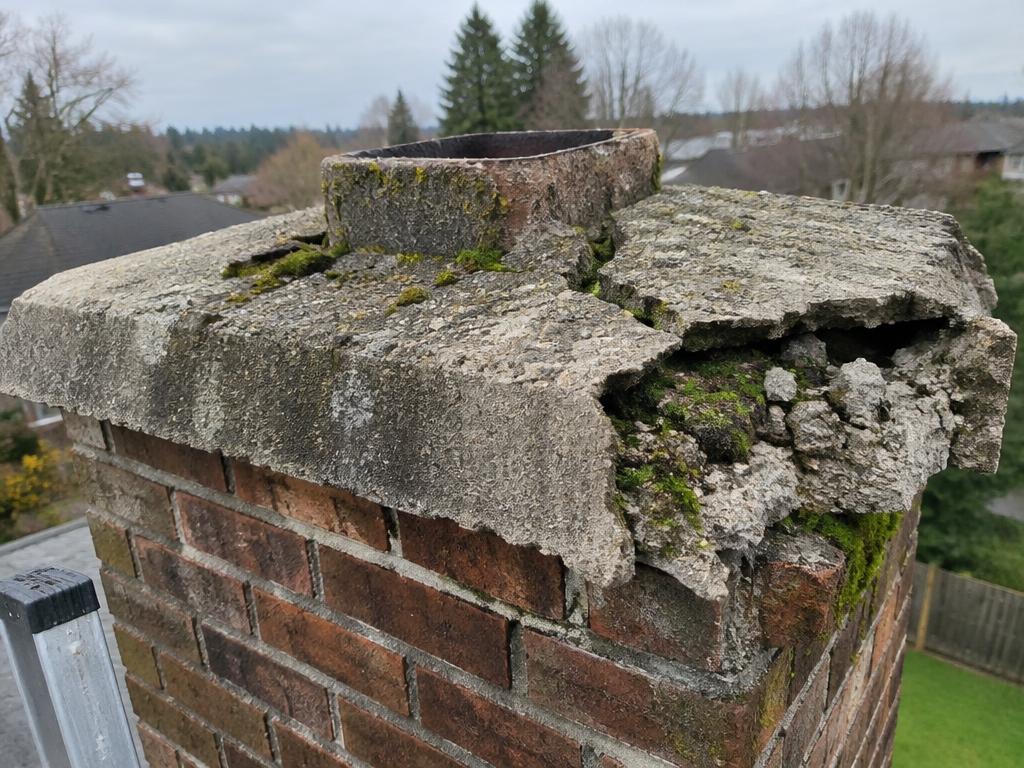 Cracked crumbling chimney crown with moss before rebuild