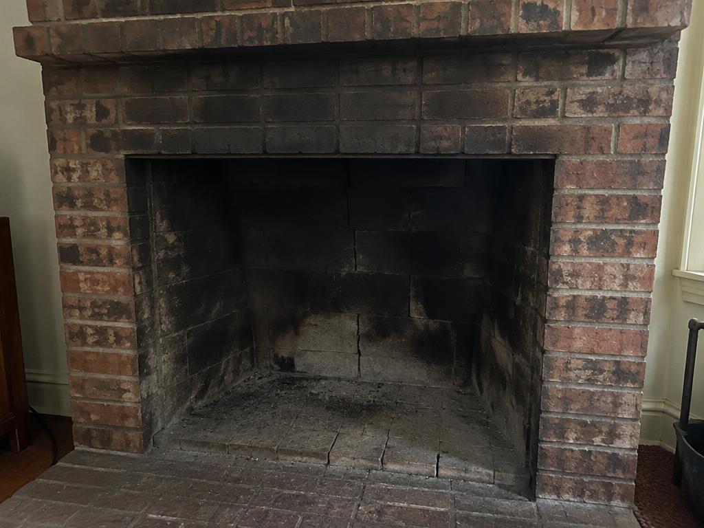 Soot-stained fireplace with cracked firebrick before restoration