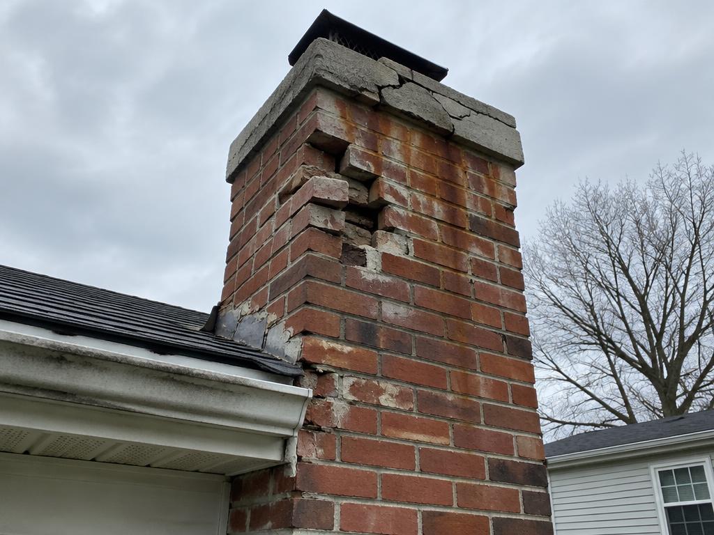 Damaged brick chimney with crumbling mortar and cracked crown before repair